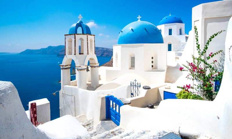Stroll among the white-washed houses with vibrant blue roofs, Santorini, Greece.