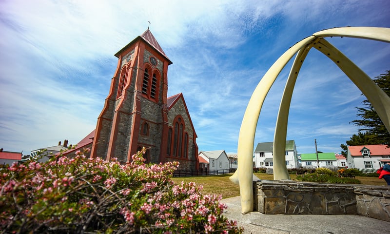 A whalebone arch leads to a pretty red brick Catholic church in Stanley, Falkland Islands.