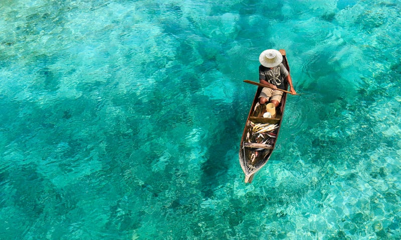 A traditional fisherman searches the clear tropical seas for schools of fish.