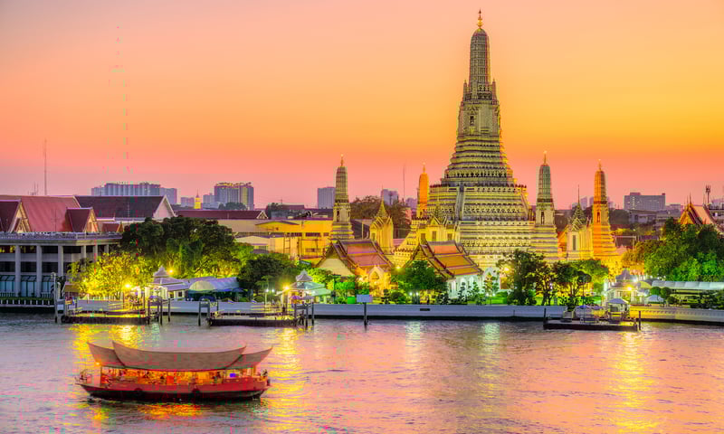 The gleaming spires of Bangkok, Thailand's Wat Arun or Temple of Dawn, beside the Chao Phraya River.