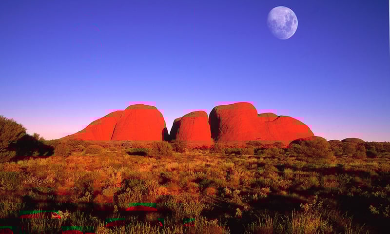 The moon over Uluru appears extra bright and clear against the dark, unpolluted desert sky.